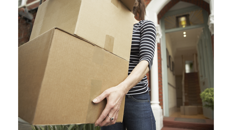 Woman carrying brown boxes from house