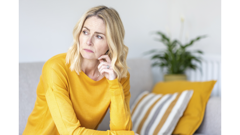 Thoughtful woman looking away while sitting at home