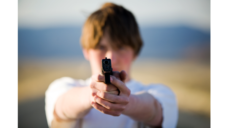teenager pointing handgun at camera