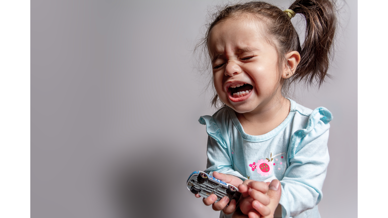 Close-Up Of Crying Baby Girl Against Gray Background