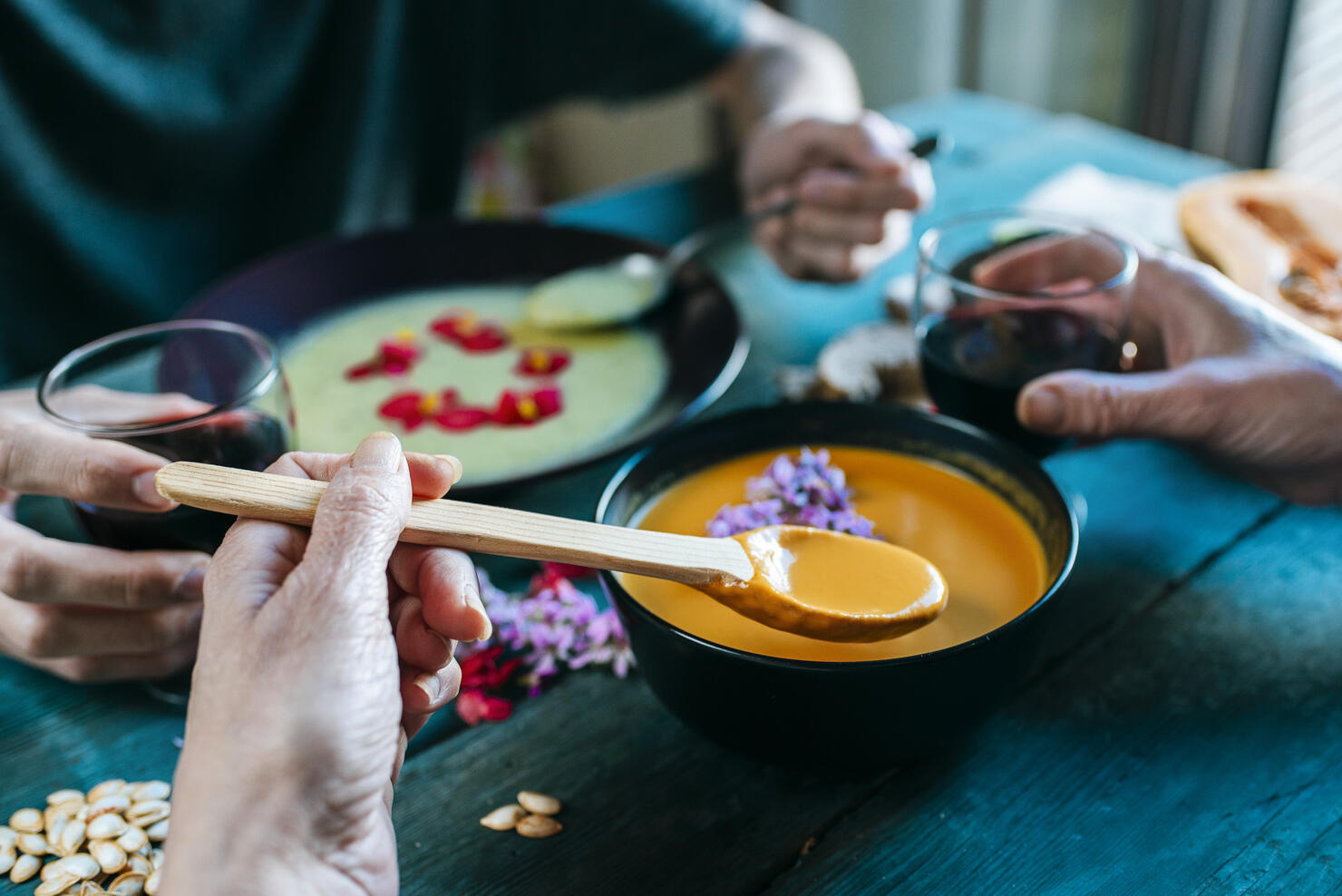 Hand of woman eating creamed pumpkin soup and drinking red wine