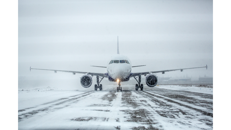 Airliner on runway in blizzard. Aircraft during taxiing during heavy snow. Passenger plane in snow at airport. Modern twin-engine passenger airplane taxiing for take off at airport during snow blizzard