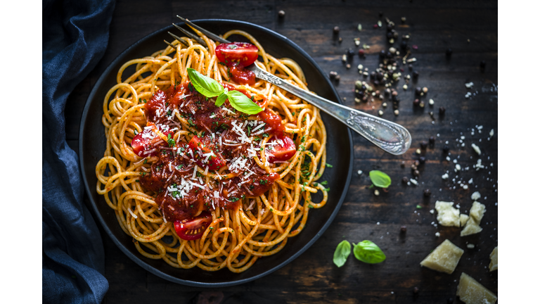 Spaghetti with tomato sauce shot on rustic wooden table