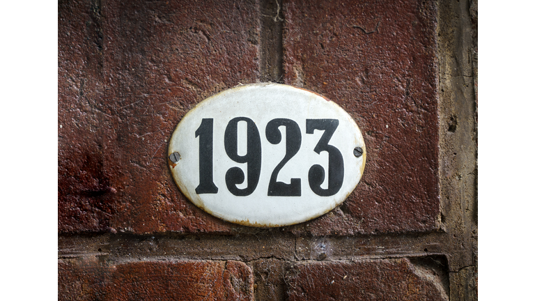 Sign with the house number 1923 on the background of the wall.