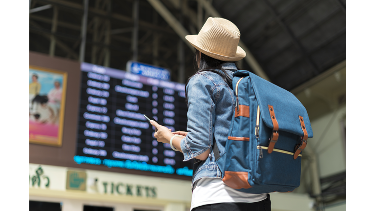 Young woman checking her train in timetable board