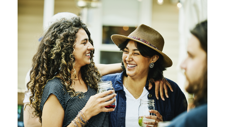 Medium shot of smiling female friends embracing while dining at food truck