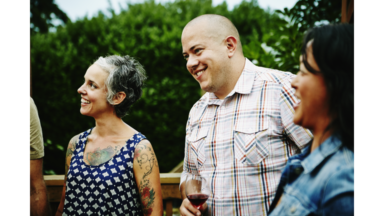 Laughing man drinking wine with friends on deck