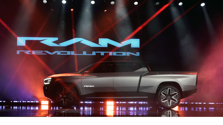 Small RAM Revolution pickup truck in silver against a red, purple, and black background with the name in light blue.