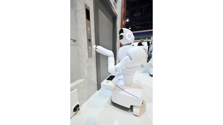 Two-armed white humanoid robot pressing the button to call the elevator.