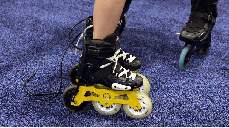 Large pair of motorized black inline skates with three wheels each.