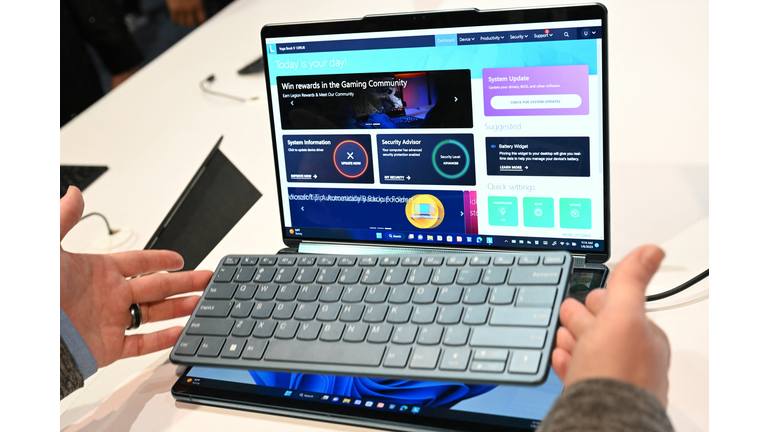 Laptop showing dual screens on both the top and bottom halves of the laptop and two hands holding a physical keyboard above it.