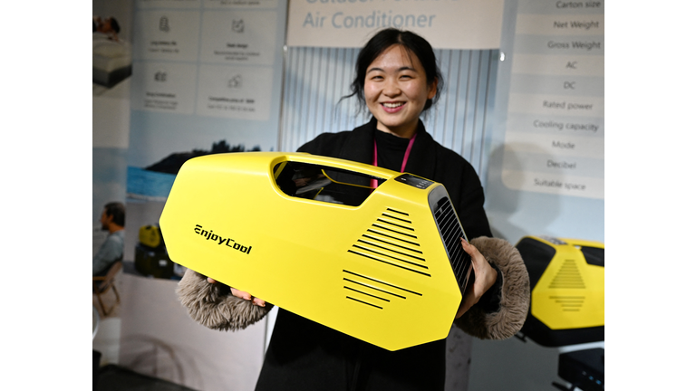Asian woman holding a yellow 7-sided portable AC unit with a handle.