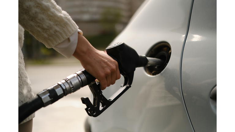 A woman using a gas pump to refuel vehicle during energy crisis