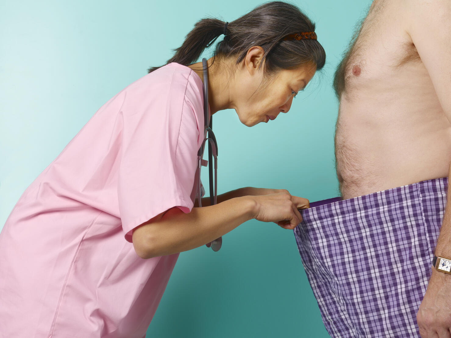Female doctor looking down into barechested man's pants, profile