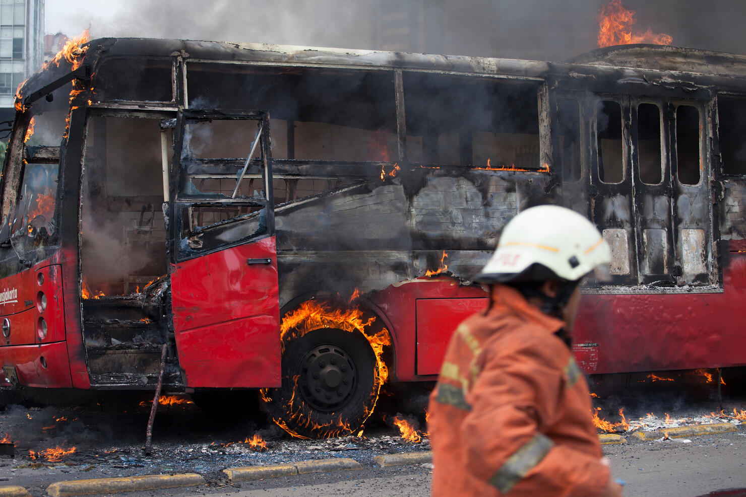 Firefighter Standing By Bus Burning On Street