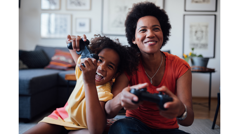 Front view of a mother and daughter playing video games together