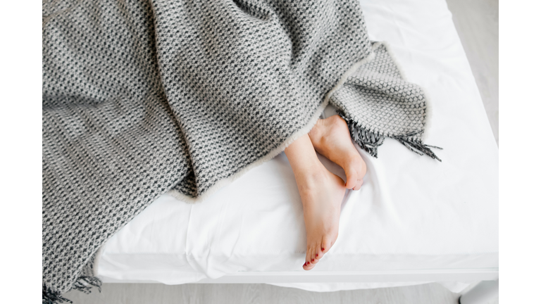 Female feet under blanket flat lay