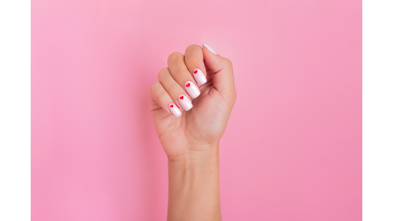 Beautiful female hand with white manicure, hearts design