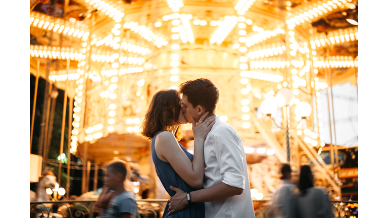 Couple kissing near the marry-go-round in the park