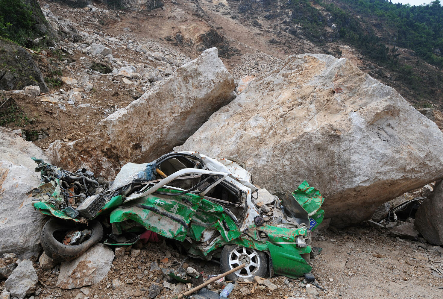 A demolished taxi crushed by boulders in