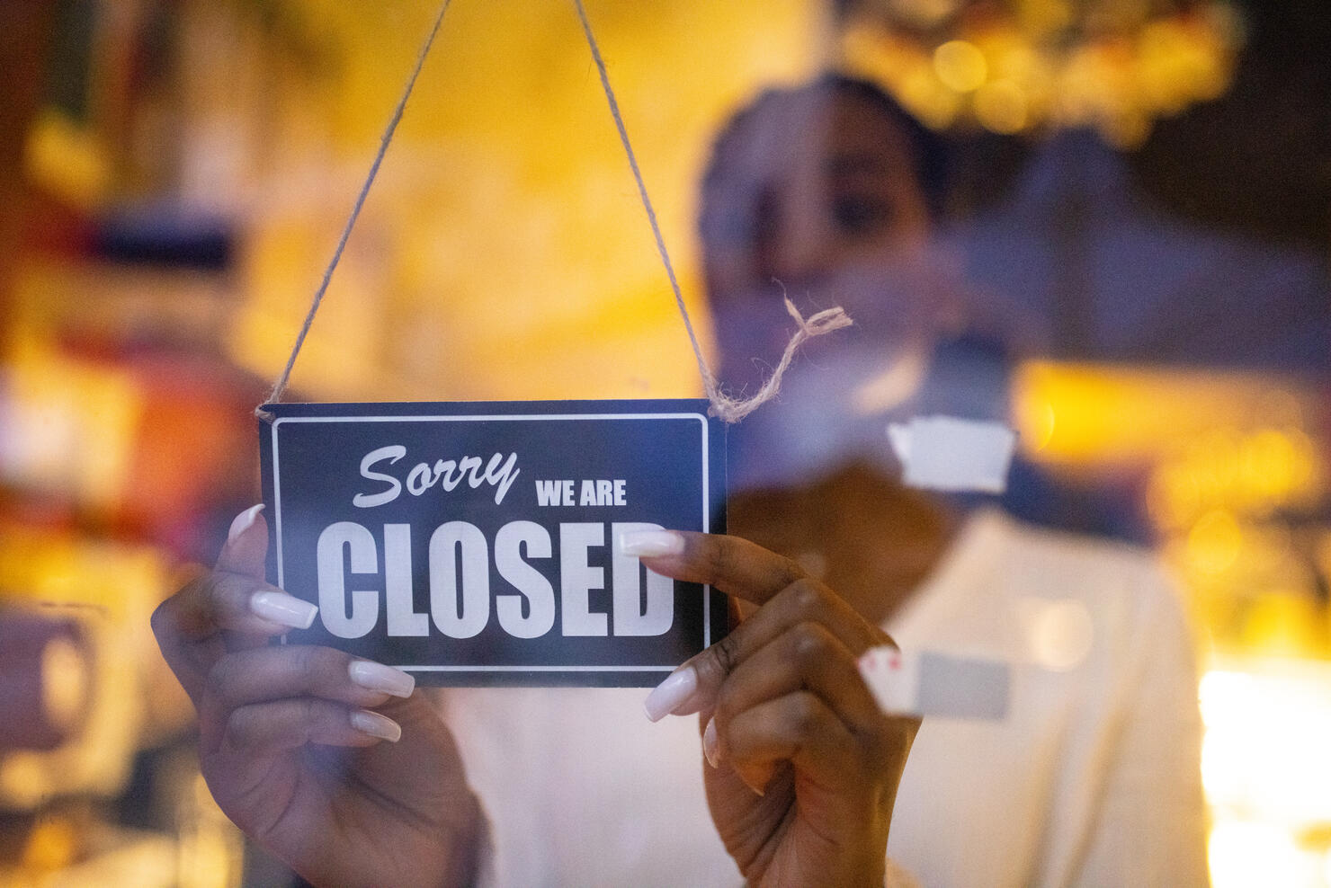 Woman putting closed sign on door of coffee shop