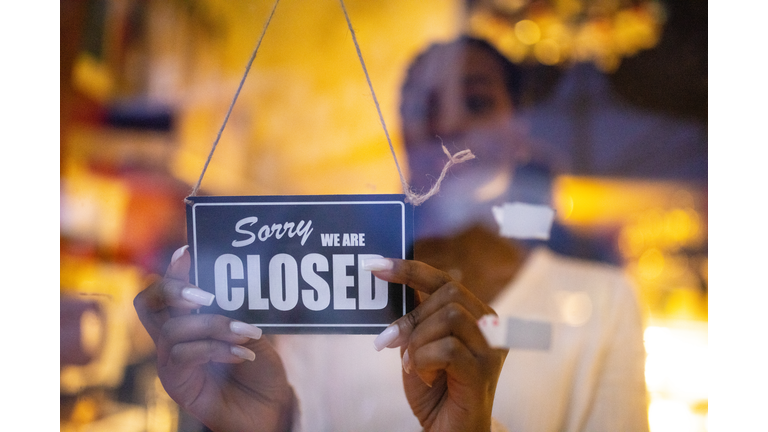 Woman putting closed sign on door of coffee shop