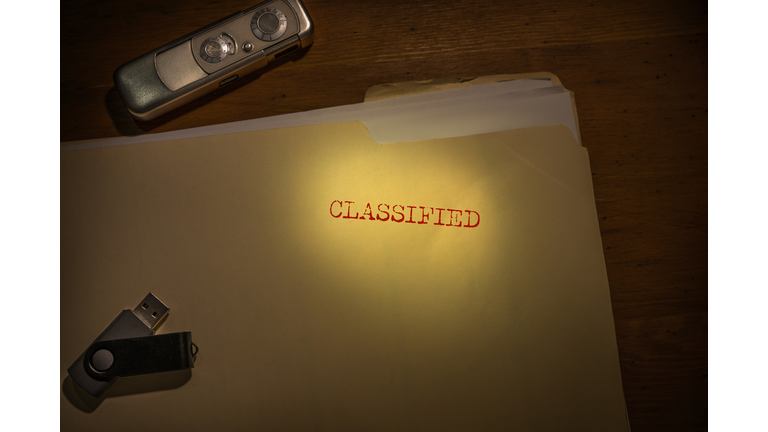 Folder marked Classified with spy camera and thumb drive