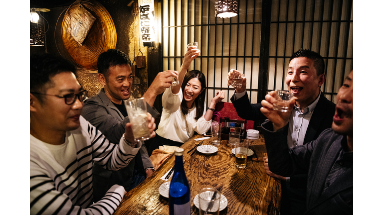 Co-workers in Japanese restaurant toasting drinks