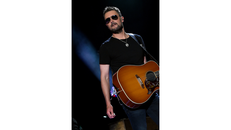 Eric Church wearing a black shirt, medallion necklace, and black sunglasses.