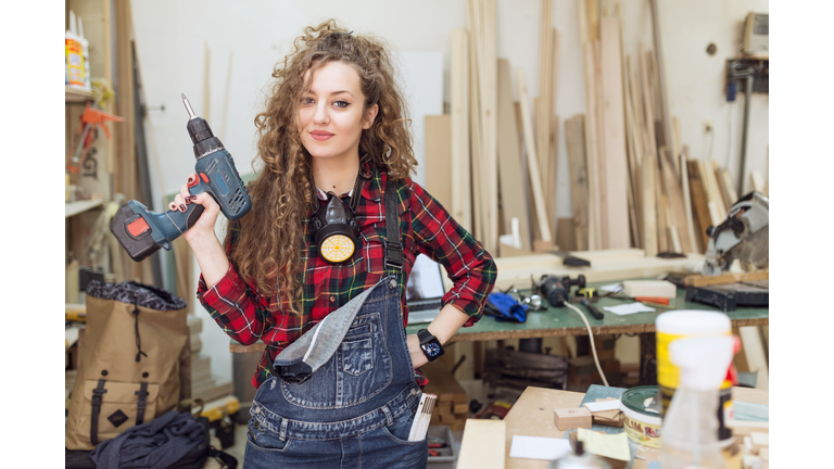 Woman carpenter standing confidently in his workshop
