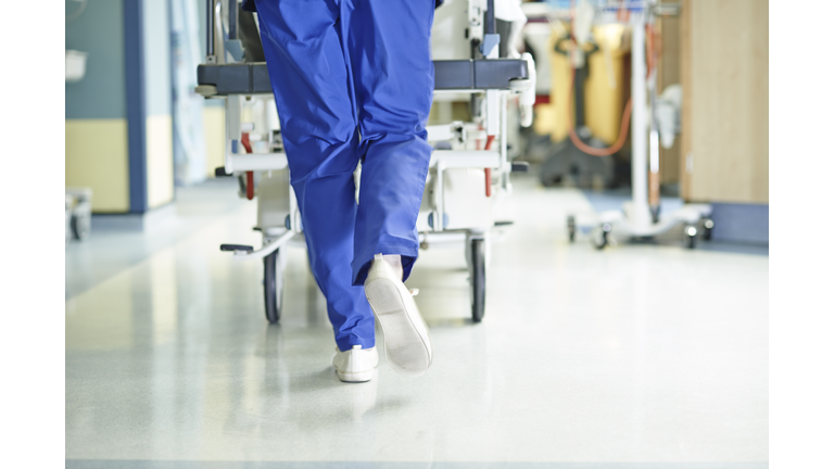 Legs of medic running with gurney along hospital corridor