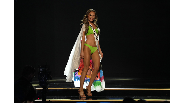 Brunette in green swimsuit and white cape.