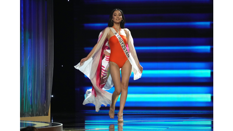 Brunette in red one-piece swimsuit and white and red cape.