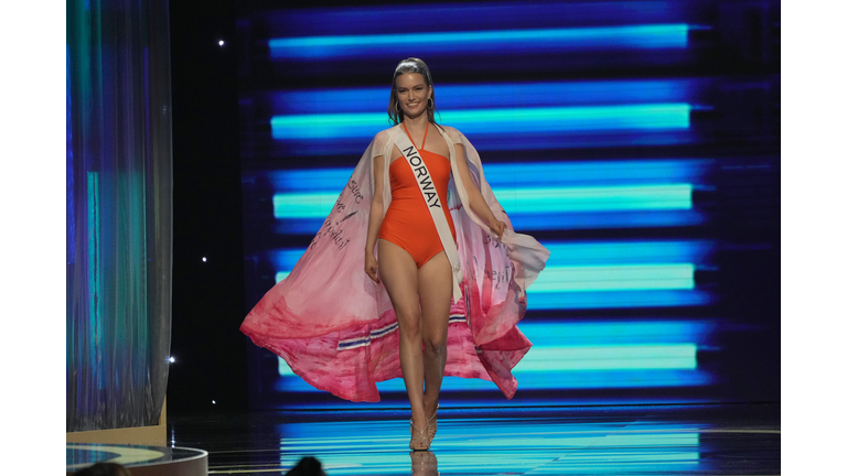 Blonde in red one-piece swimsuit and ombre white to red cape.