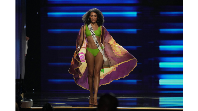 Brunette in light green swimsuit and multi-colored cape.