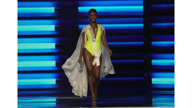 Dark-skinned brunette in bright yellow one-piece swimsuit and white cape.
