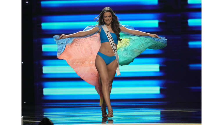 Brunette in blue swimsuit and multi-colored cape.