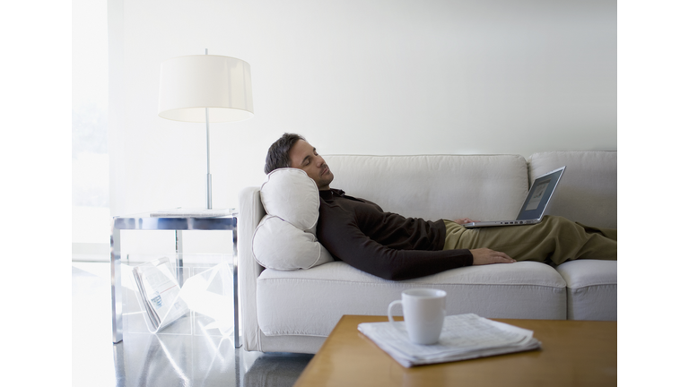 Man with laptop sleeping on sofa