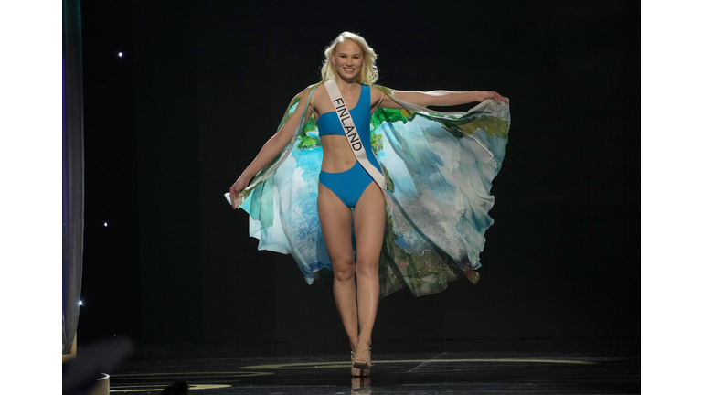Blonde in blue swimsuit and cape in shades of blue and green.