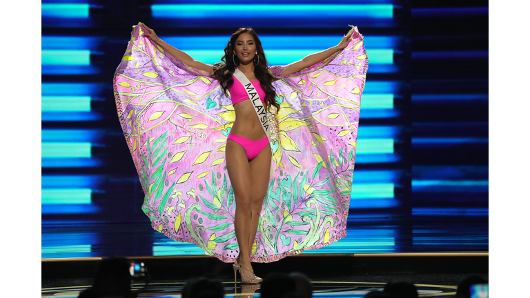 Brunette in pink swimsuit and cape in pastel colors.
