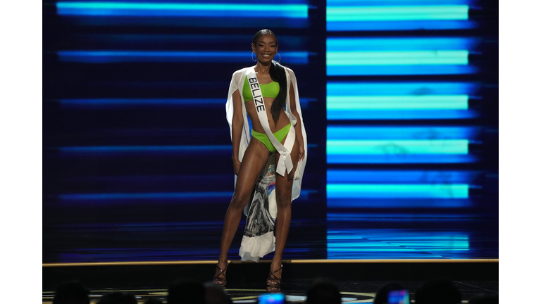 Dark-skinned brunette in green swimsuit with white cape