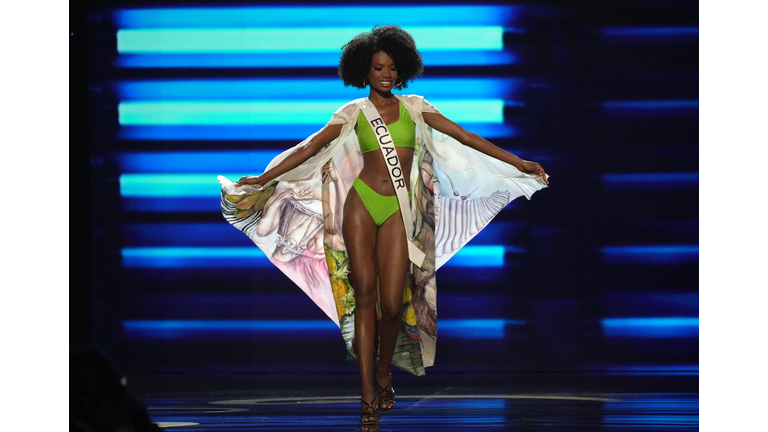 Dark-skinned brunette in green swimsuit and cape in soft colors.