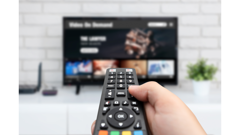 Man watching TV, remote control in hand