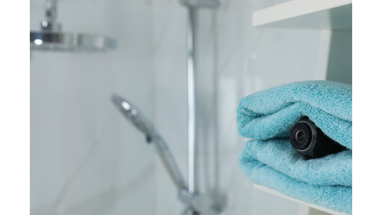 Camera hidden between towels in bathroom, space for text