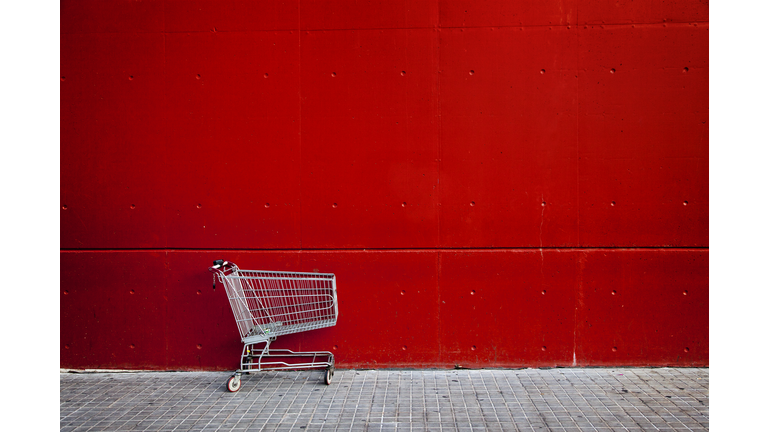 Shopping cart in front of a red wall