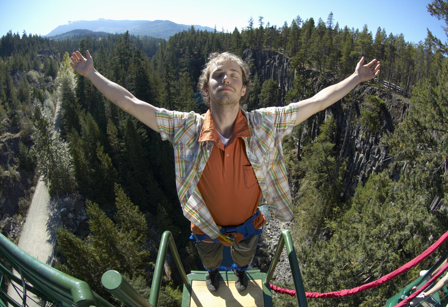 Young man standing on bungee jump platform, (wide angle)