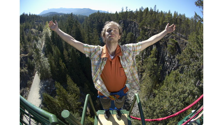 Young man standing on bungee jump platform, (wide angle)