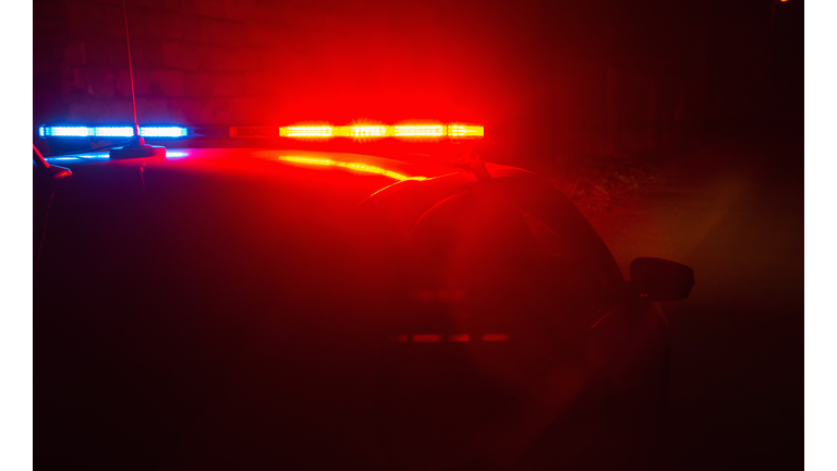 Police car with red and blue flashing lights on empty night street background, crime scene, night patrolling the city, fight against looting during quarantine.