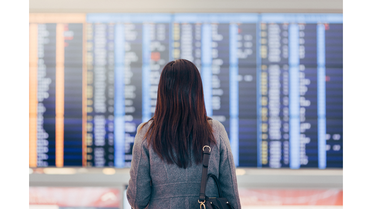 Woman looking up and checking schedule at airport