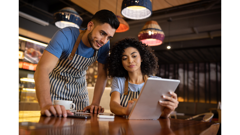 Team of waiters working at a restaurant and looking at the menu on a tablet